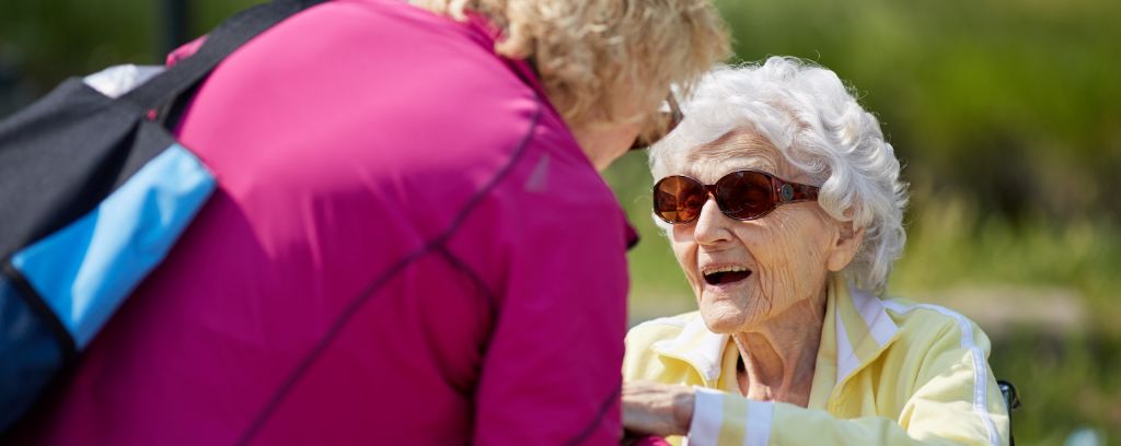 Resident and care partner talking and smiling outside