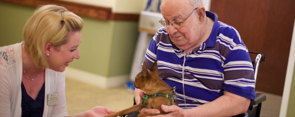 Team member visiting with resident and his dog